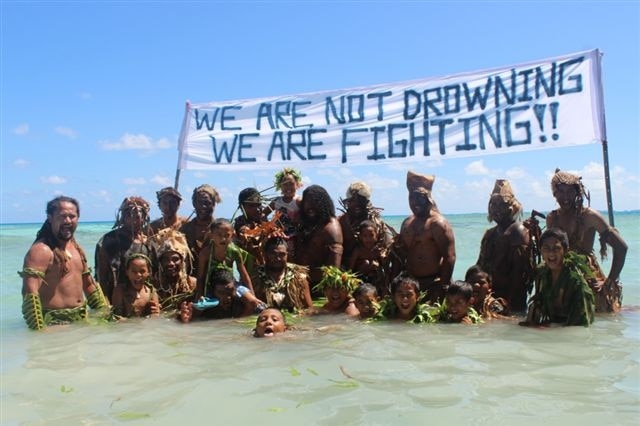 Tokelauns protest climate change under a sign saying "we are not drowning, we are fighting"