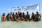 Tokelauns protest climate change under a sign saying "we are not drowning, we are fighting"