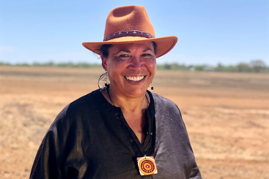 Suzanne Thompson smiles while wearing a hat outside in the sun.