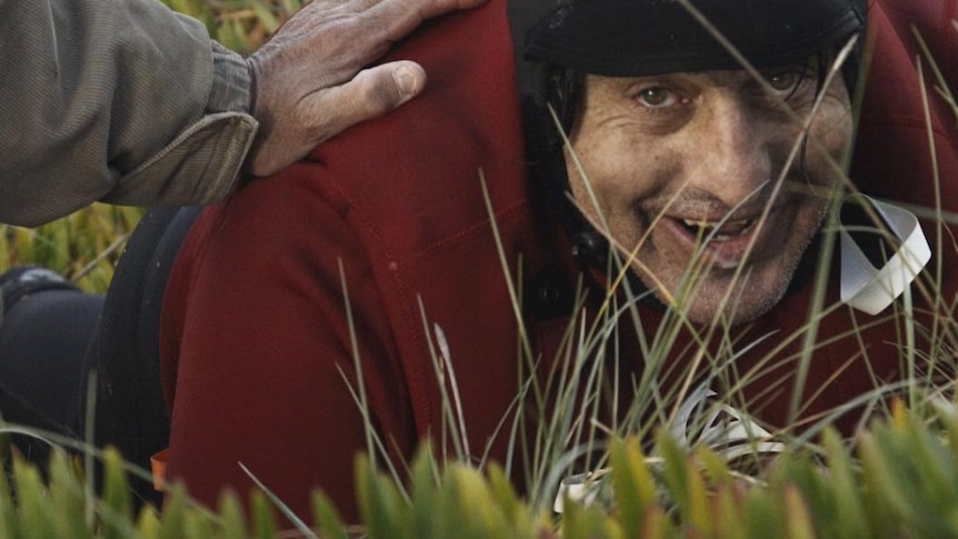 A man grins as he lies in the grass.