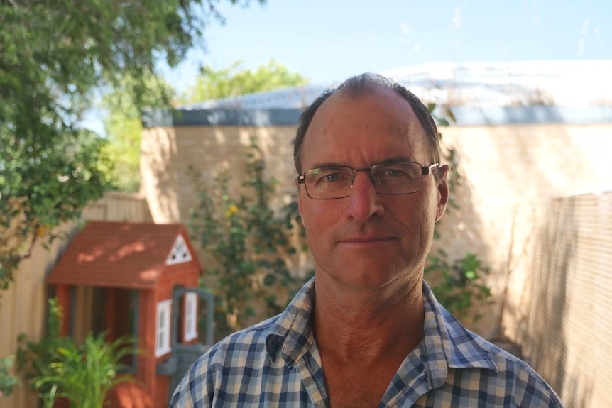 Australian National Rabbit Council president Mark Page is standing in a backyard