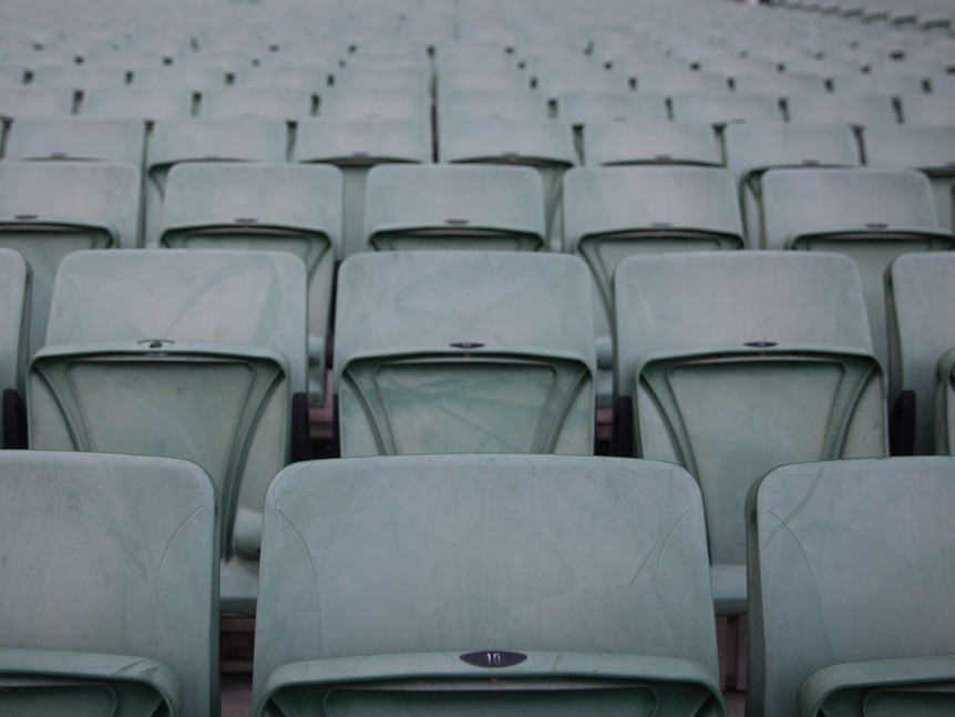 Lines of empty green seats fill the frame