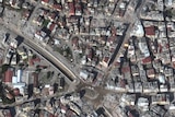 A satellite image of a city where several buildings have collapsed. 