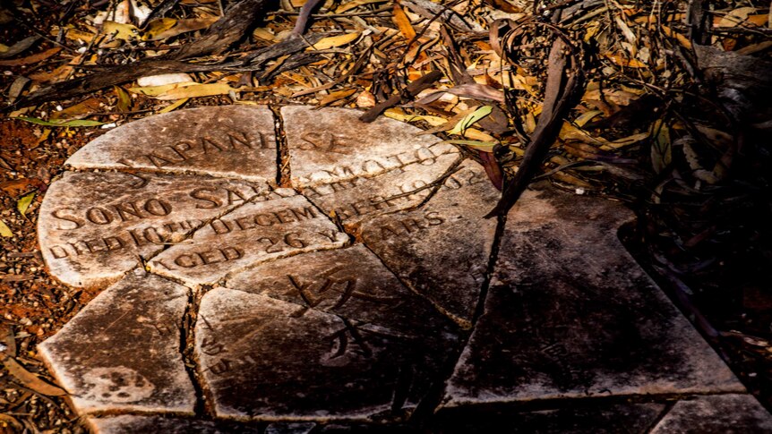 Image of a smashed headstone, bearing some Japanese characters, in an abandoned cemetery at Kanowna.