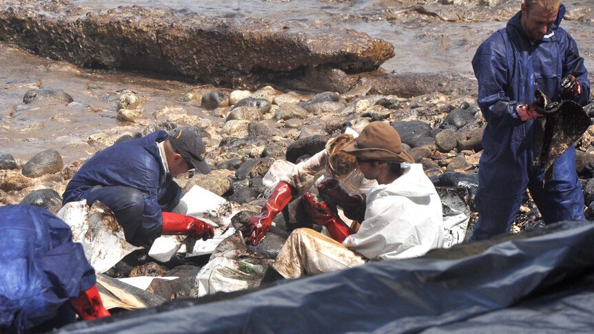 Volunteers clean up an oil spill in Flying Fish Cove