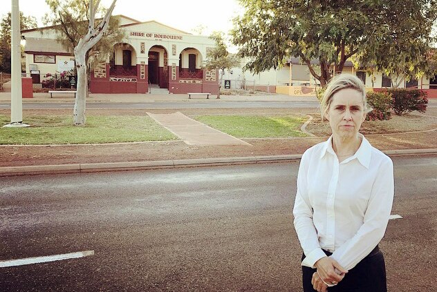 Simone McGurk stands by the road in Roebourne, with the shire offices in the background.