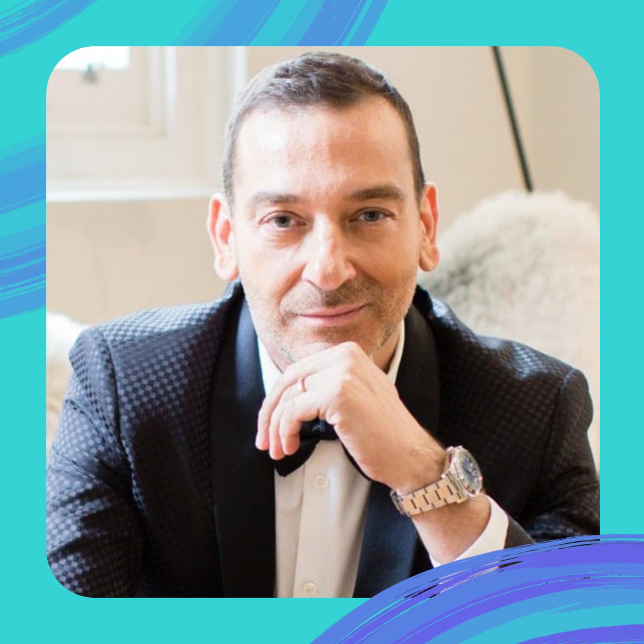 A portrait of Vinko wearing a tuxedo and a bowtie, with his chin on his hand.