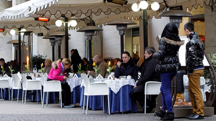 People sit at outdoor tables at a restaurant in Italy.