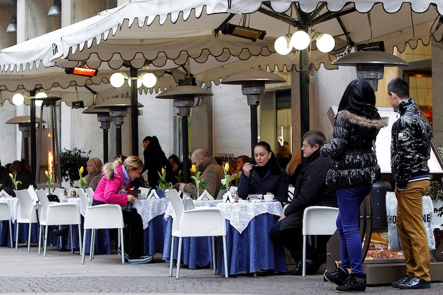 People sit at outdoor tables at a restaurant in Italy.