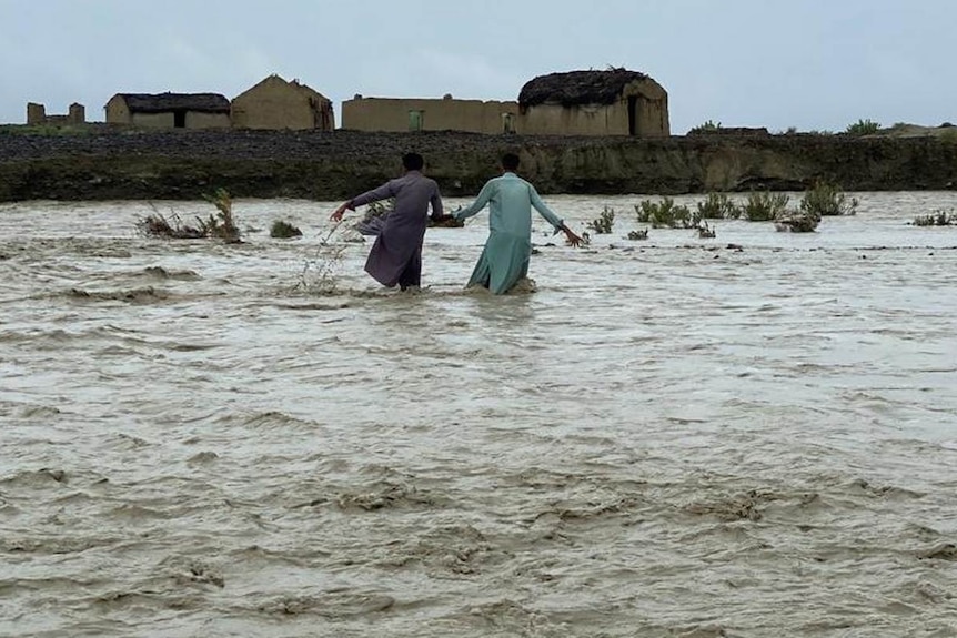 Two men cross floodwaters in Awaran district, in Balochistan province.