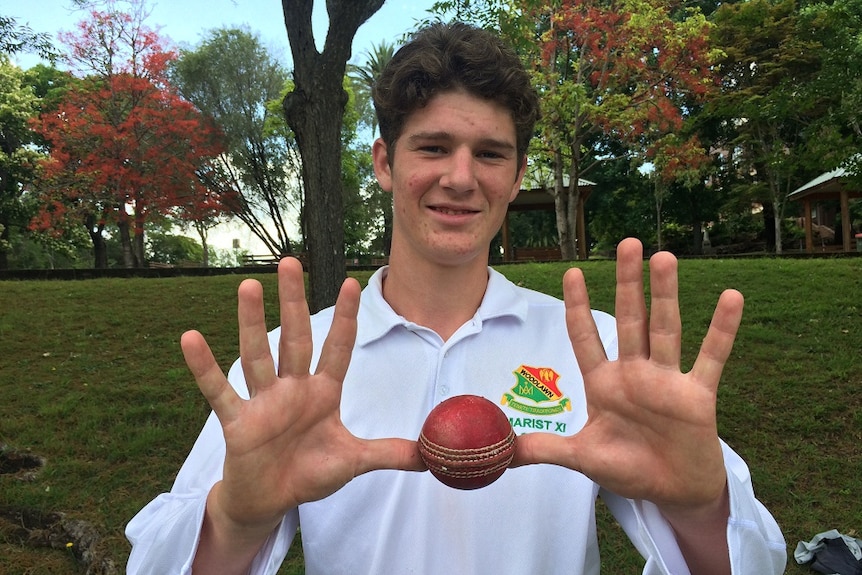 James Fennamore holds up 10 fingers and a cricket ball to celebrate his rare feat of dismissing an entire team