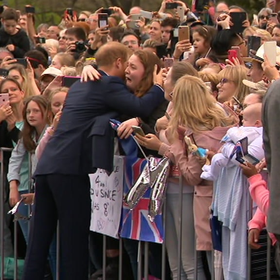 Prince Harry hugs a woman as she bursts into tears in a crowd of people.