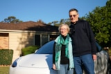 Pair stand together infront of white car