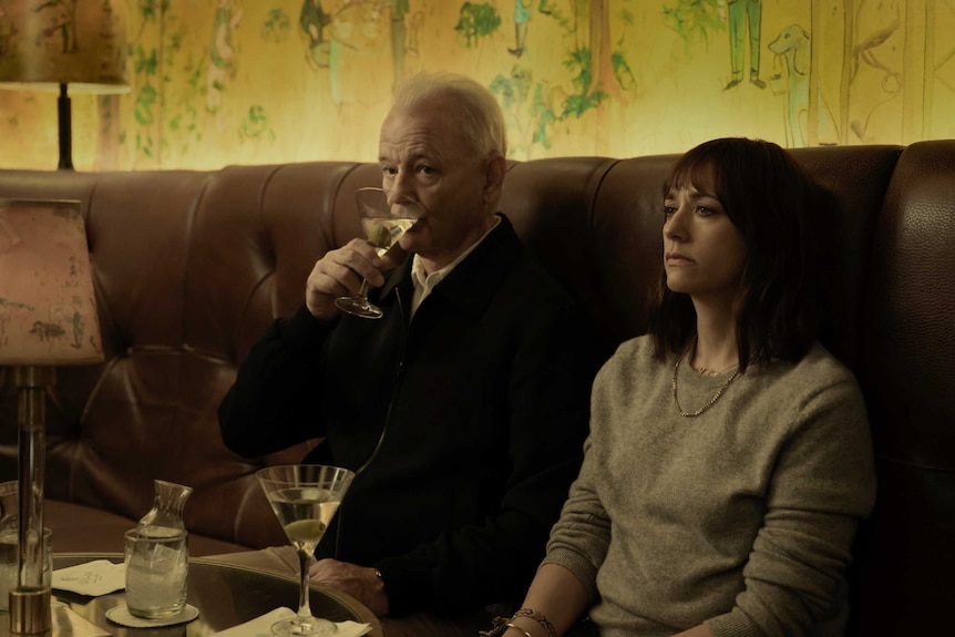 Bill Murray sips a martini next to Rashida Jones sitting in a restaurant in the film On the Rocks