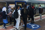 Commuters gathering to board at an Adelaide Metro train's doors