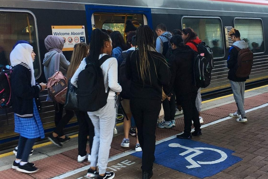 Commuters gathering to board at an Adelaide Metro train's doors