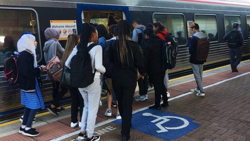 Commuters gathering to board at an Adelaide Metro train's doors