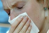 A woman sneezes into a tissue