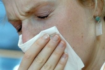 A woman sneezes into a tissue