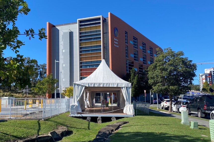A tent used to perform COVID-19 tests standing empty in a grassed area in front of a high-rise.