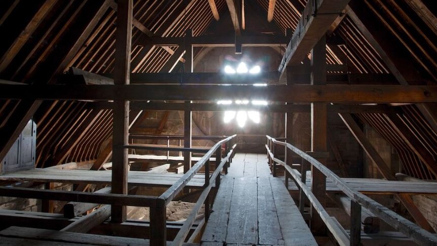 A wooden walkway surrounded by beams leading towards a window