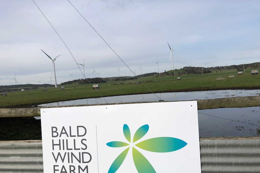 A sign on a fence that says "Bald Hills Wind Farm".