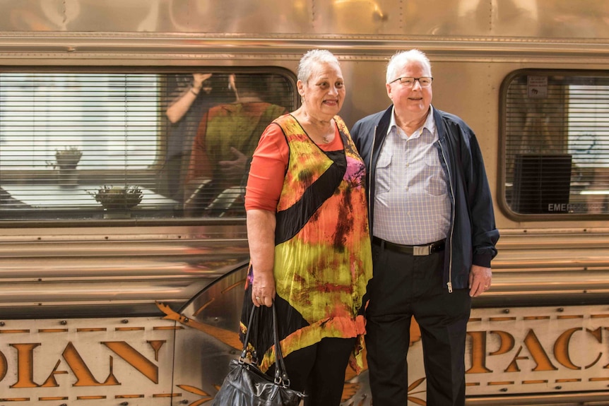 A man and woman standing in front of a train about to board