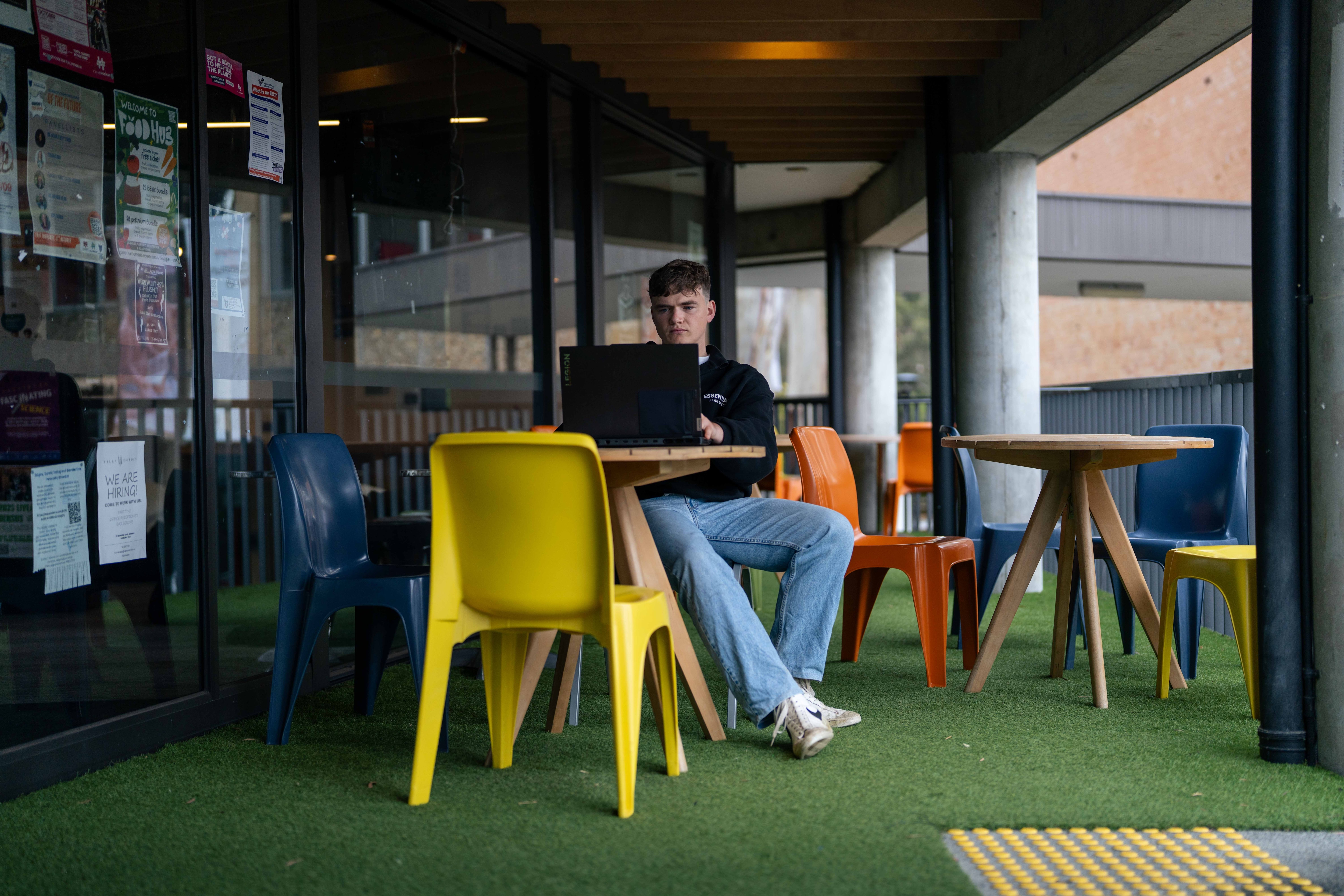 Man sits on table at university using his laptop