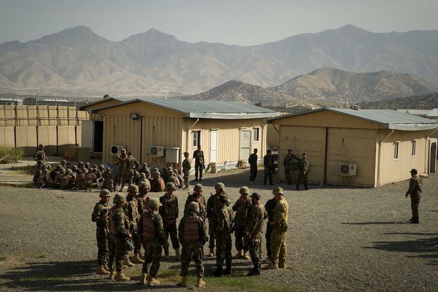 One group of soldiers sits in a circle and another stands at a facility in Afghanistan.