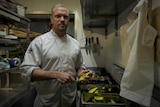 A cook stands in a commercial kitchen.