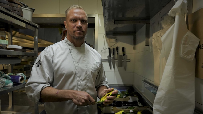 A cook stands in a commercial kitchen.