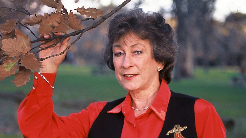 A woman holding a tree branch, smiling.