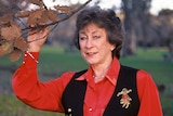 A woman holding a tree branch, smiling.