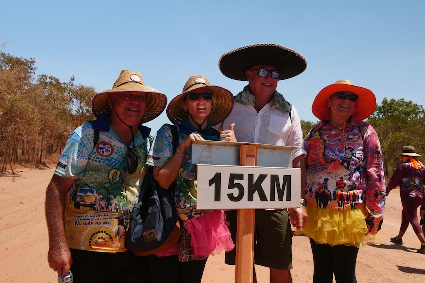 A group of people stand behind a 15 kilometre sign