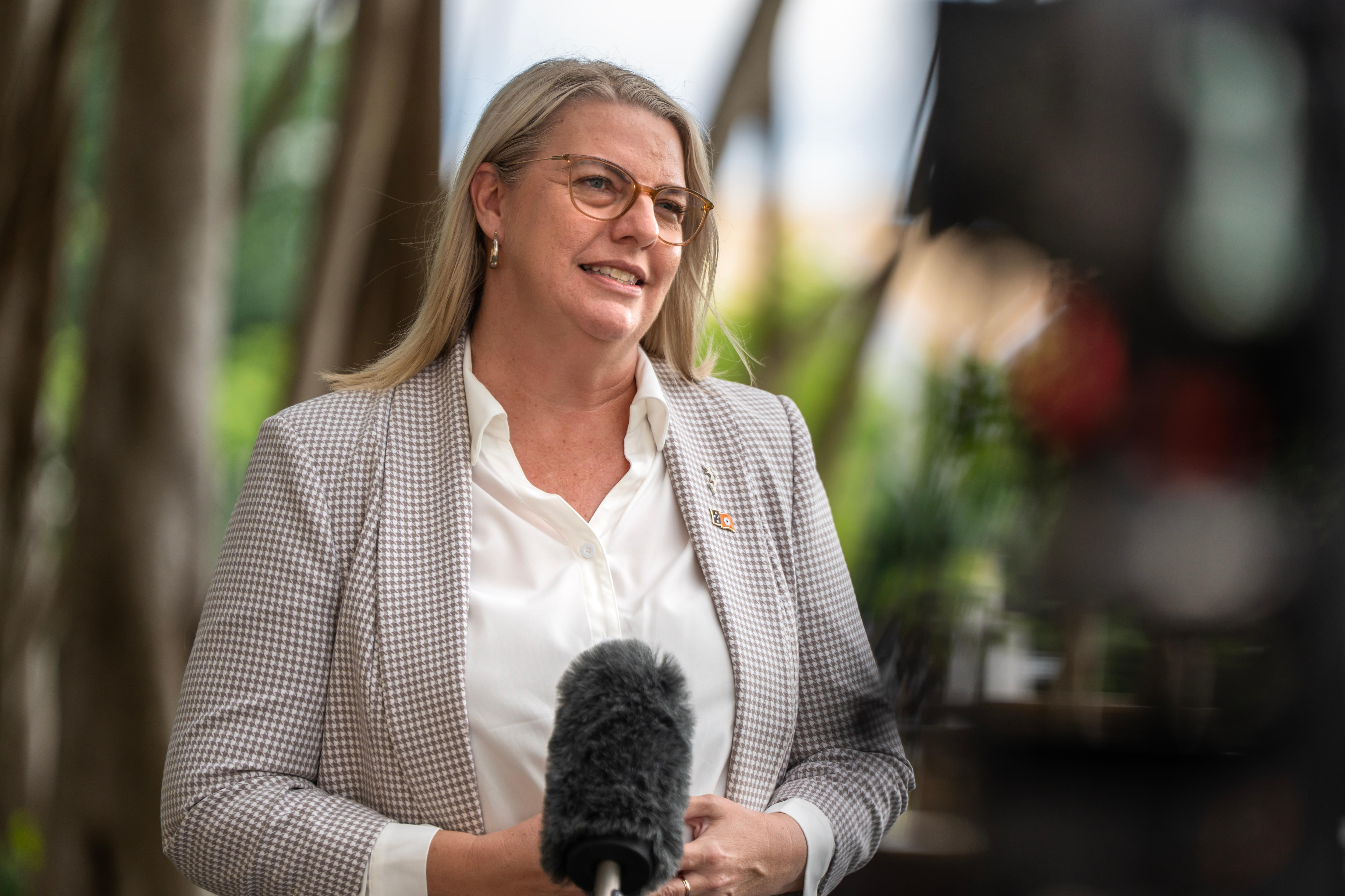 Una mujer con camisa blanca y blazer a cuadros.