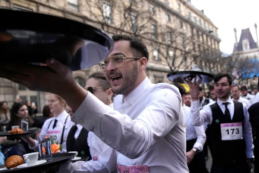 Waiters carry trays through the streets of Paris in a race.