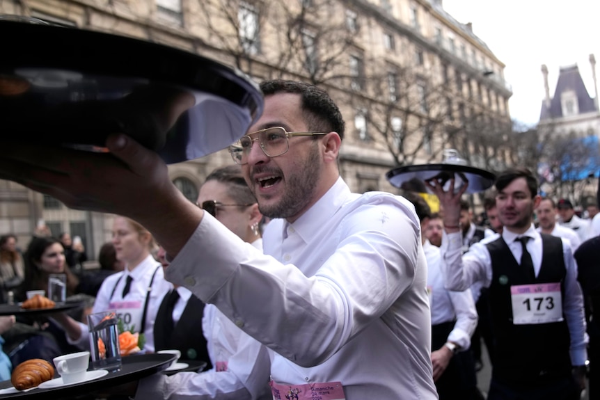 Waiters carry trays through the streets of Paris in a race.