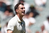 Australia bowler Pat Cummins grimaces as he runs past Pakistan batter Shan Masood at the MCG.