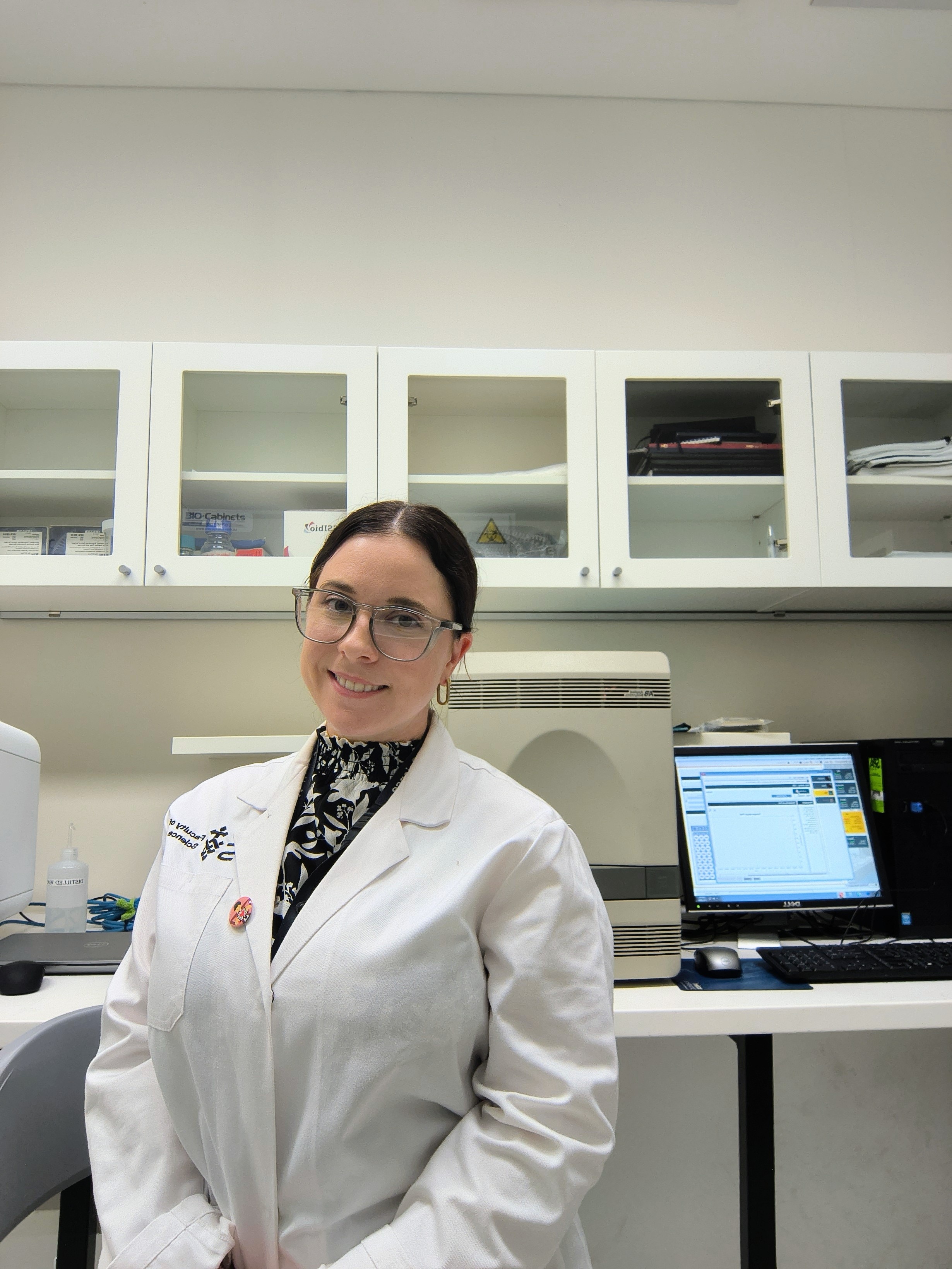 Mujer con bata blanca de laboratorio y gafas.
