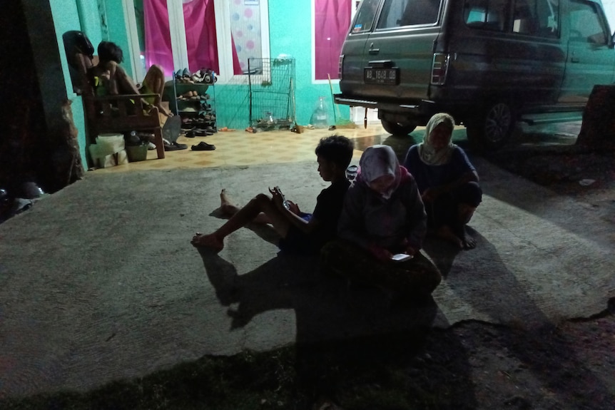 People wait outside their homes following an earthquake in Bantul district.