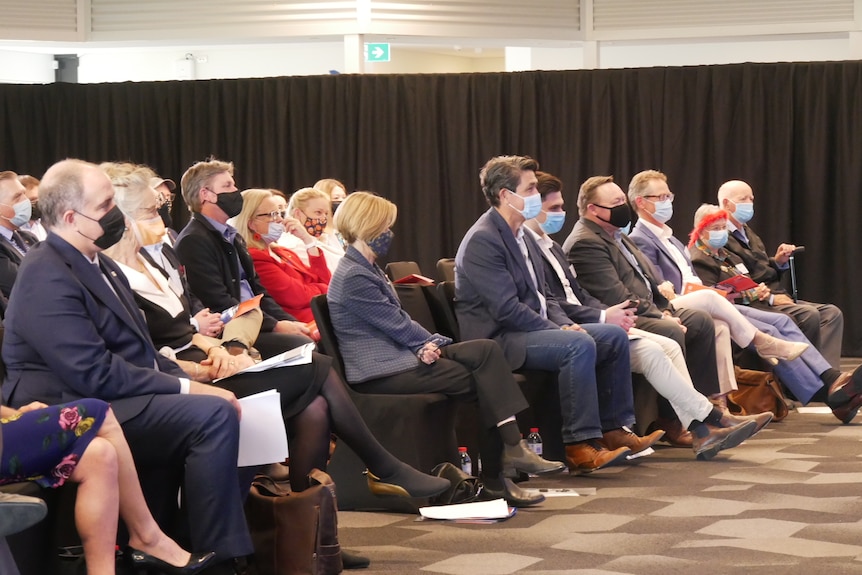 People sitting on chairs listening to a speech.