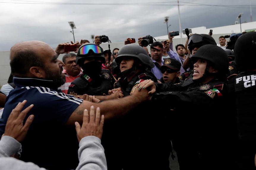 Relatives of inmates push against police outside the Cadereyta state prison.
