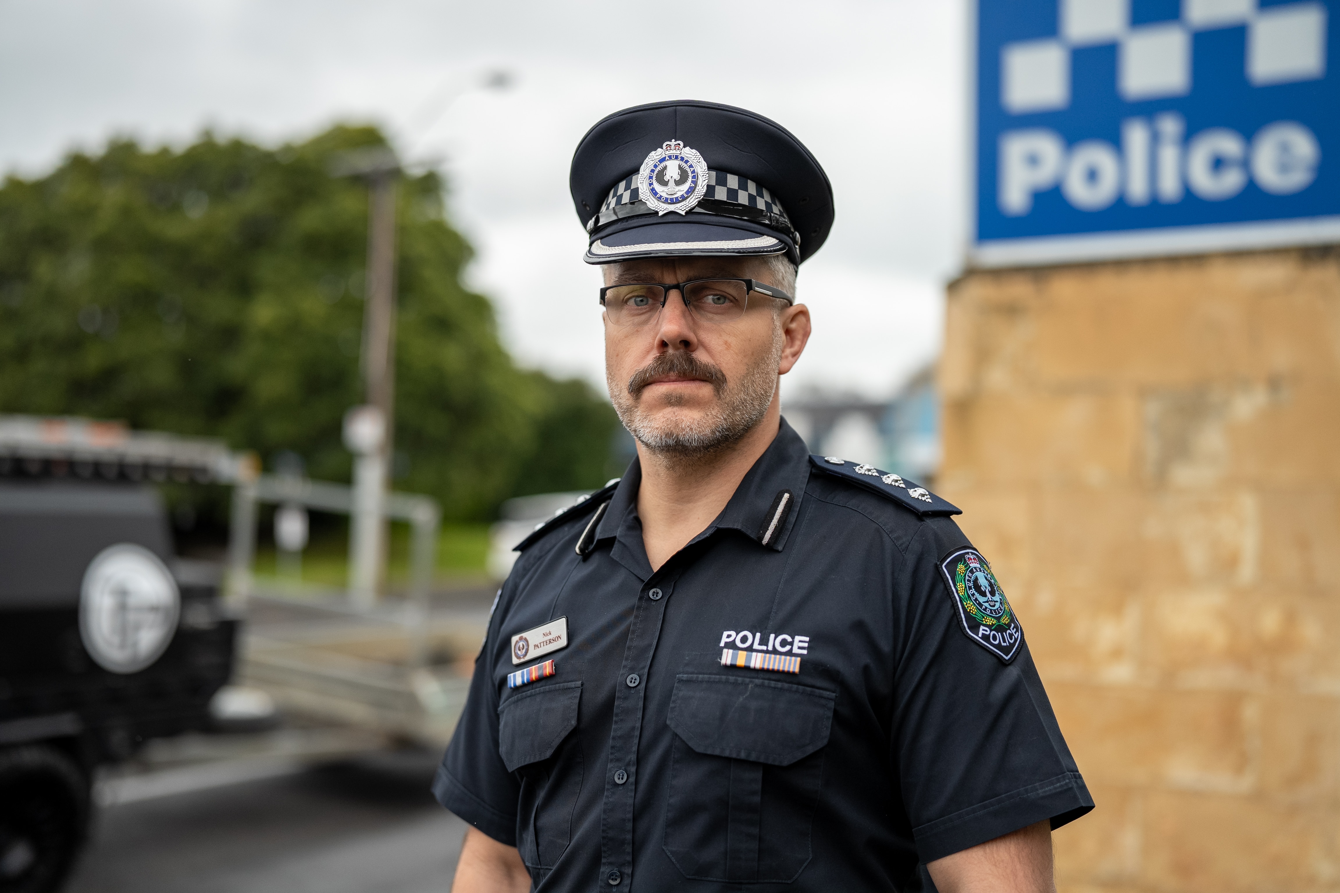 A police officer standing in front of a police sign. 