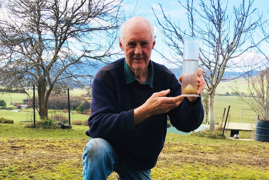 Tasmanian farmer Ian Dickenson with a rain gauge