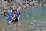 Two boys with a bucket in a stream