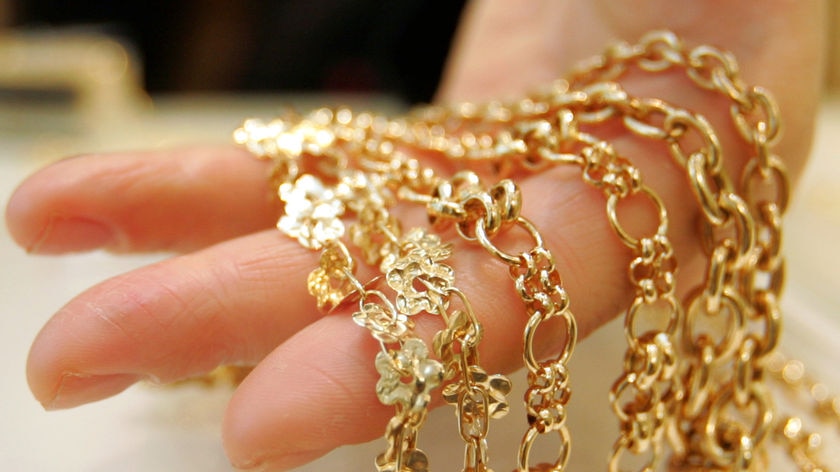 Hand holding gold necklaces displayed at Ginza Tanaka jewellery store in Tokyo in Japan