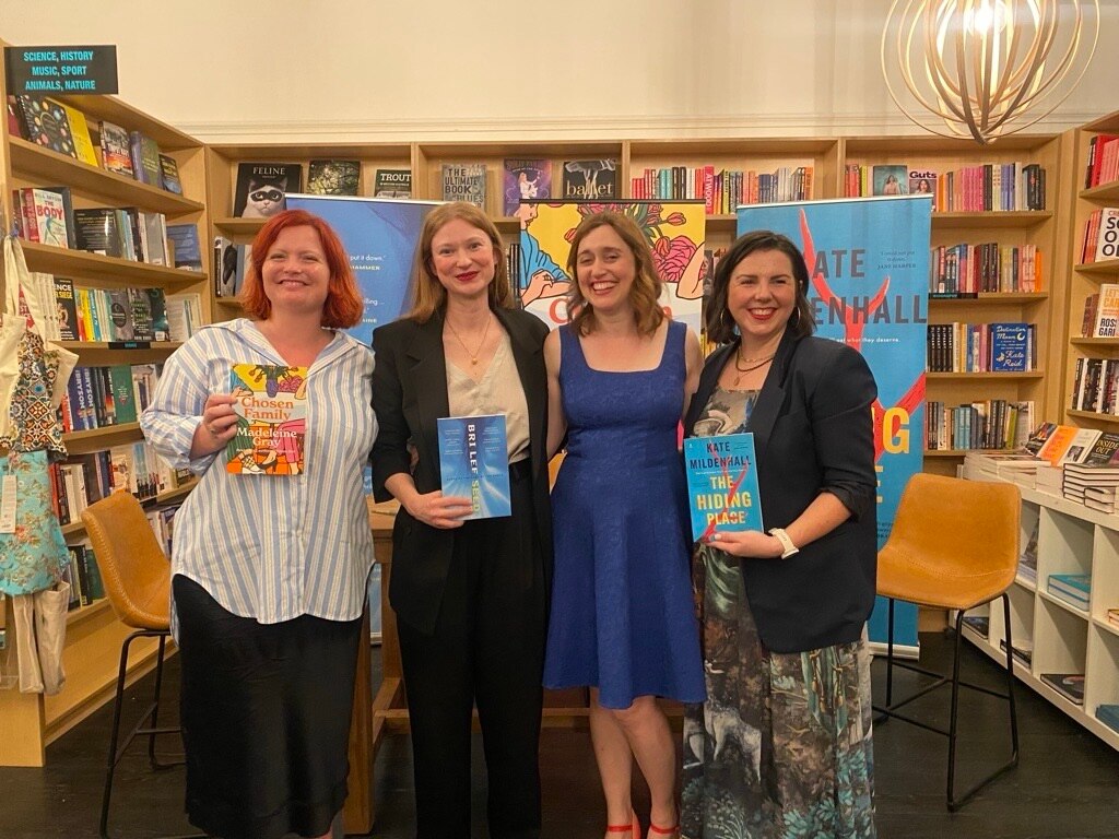 four women standing next to eachother in front of bookshelves
