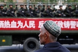 A Uighur man looks on as a truck carrying paramilitary policemen travel along a street during an anti-terrorism rally in China.