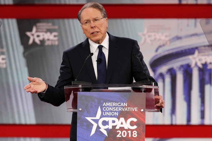 Wayne LaPierre speaks at a lectern, gesturing with one hand.