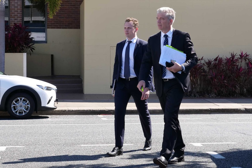 Barrister Craig Eberhardt walks with another man in a suit.